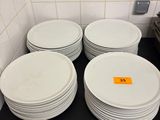 Plusieurs assiettes blanches sont empilées sur une étagère noire dans une cuisine