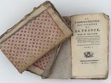 two old books are stacked on top of each other on a white surface