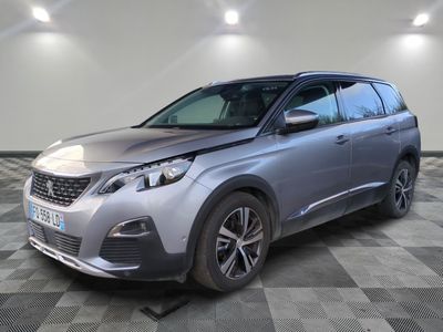 Une voiture grise est garée dans une grande pièce au sol carrelé.