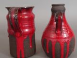 two red vases sitting next to each other on a table
