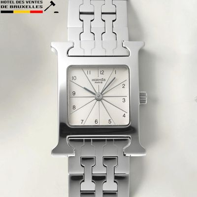 a close up of a silver watch on a white surface