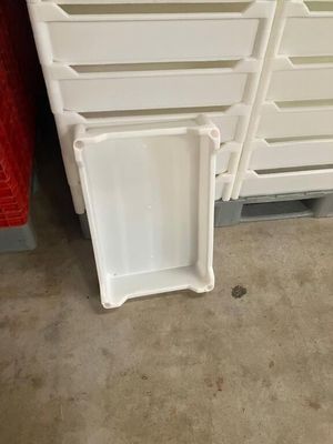 une pile de bacs en plastique blanc posée par terre