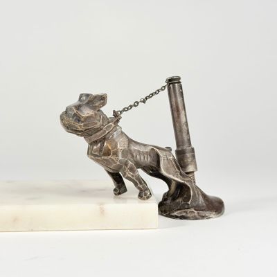 silver statue of a dog with a pen on a marble base