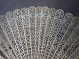a white fan with black designs on it sitting on a table