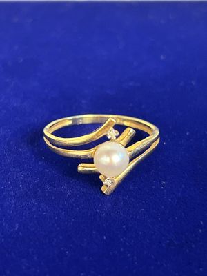 a gold ring with a pearl and diamonds on a blue surface
