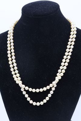 a white pearl necklace on a black mannequin