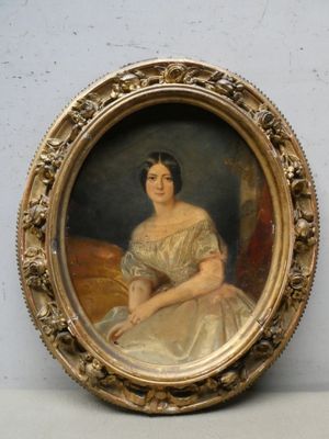 une vieille photo d'une femme en robe blanche, assise, dans un cadre doré