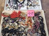 deux plateaux remplis de bijoux variés posés sur une table en bois
