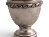 une vieille coupe en argent posée sur un socle en métal