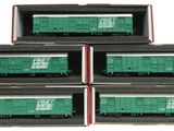 four green train cars in boxes on a white surface