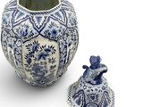 a blue and white vase with a lid next to a small figurine