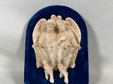 une image représentant une sculpture de deux anges posée sur un écrin en velours bleu