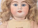 a doll with blonde hair and blue eyes sitting on a white surface