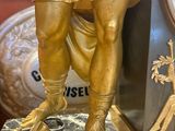 a gold statue of a roman soldier with a sword