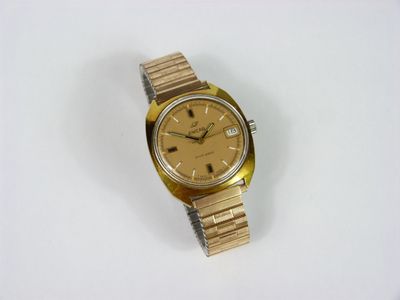une image représentant une montre en or posée sur une surface blanche, sur fond blanc