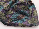 a close up of a purple and green scarf on a white surface