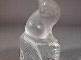 une figurine en verre représentant un chat assis sur un bloc