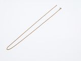 a gold necklace with a long chain on a white background