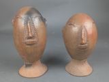 deux vases ornés de visages, posés sur un fond gris