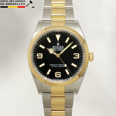 the rolex watch has a black dial and two tone steel bracelet