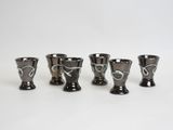 four black and white shot glasses sitting on top of a white table