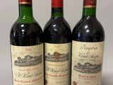 trois bouteilles de vin rouge sont alignées sur une surface blanche