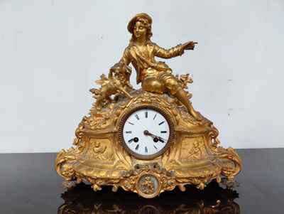 une horloge en or surmontée d'une statuette, posée sur une table