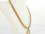 a gold chain necklace with a feather pendant on a mannequin