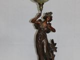 une statue représentant une femme tenant une lampe posée sur une table
