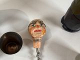 a bottle opener with a face on it next to a wine bottle