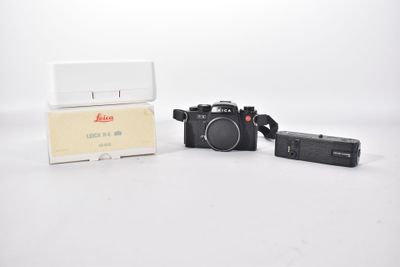 a black camera and a white box on a white surface