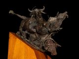statue of a man on a horse and a bull on a wooden base