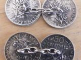 trois pièces d'argent munies de chaînes, posées sur une table en bois
