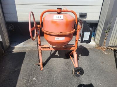 une bétonnière orange posée sur une dalle de béton