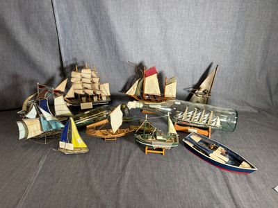 de nombreux types de bateaux miniatures dans une bouteille, posés sur un canapé