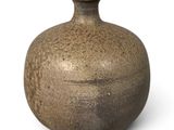 un vase brun posé sur une surface blanche