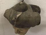 a statue of a man on a rock hanging from a hook