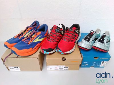 several pairs of running shoes sitting on top of a cardboard box