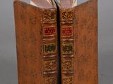two old books are sitting on top of each other on a table