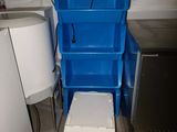 une poubelle bleue située à côté de toilettes blanches