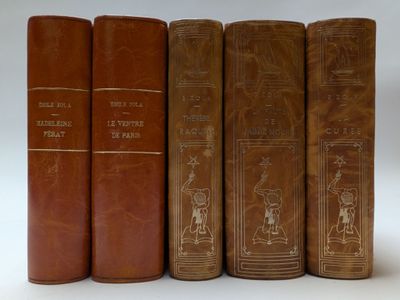 quatre vieux livres posés l'un sur l'autre sur une surface blanche