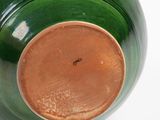 a green vase with a brown lid sitting on a white surface