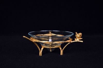une image représentant un bol en verre posé sur un socle, sur lequel est perché un oiseau