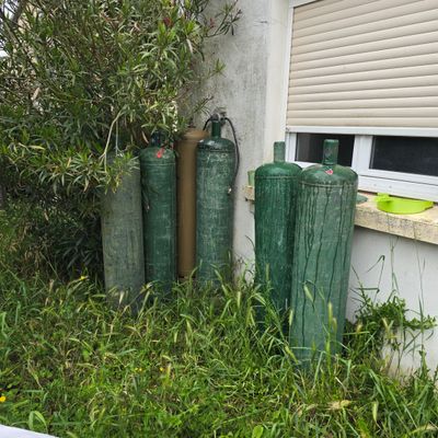 three green cylinders in front of a building with a window