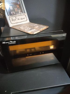 un ordinateur portable posé sur un micro-ondes, lui-même posé sur une table