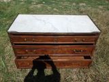 une commode au plateau en marbre posée dans l'herbe