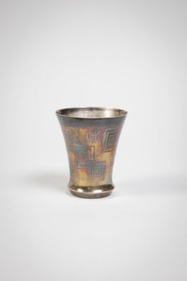 a silver cup with a design on it on a white surface