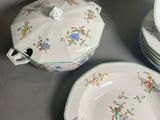 four plates and a bowl with a lid on a table