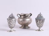 trois vases en argent posés l'un à côté de l'autre sur une surface blanche
