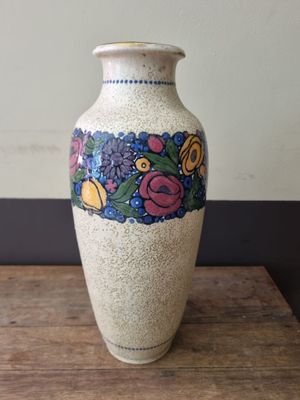 a white vase with flowers on it sitting on a wooden table